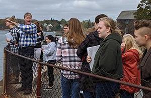 man instructing students outside at harbor