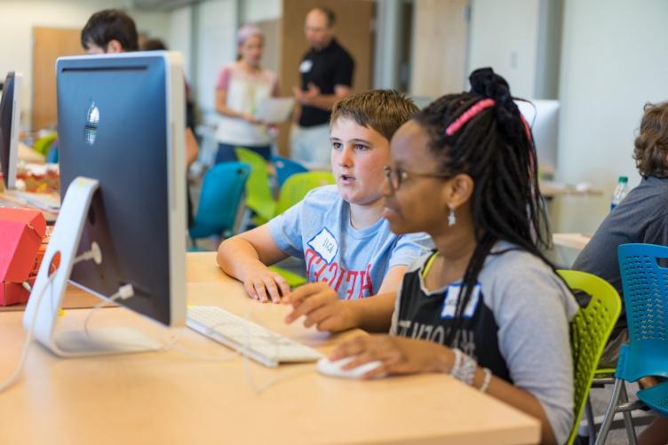 两个中学生，一个男孩和一个女孩，一起在电脑上工作.