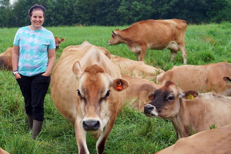吉莉安·纽博尔德站在主要研究有机乳制品研究农场泽西奶牛的田野里.