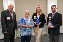 Four people -- two men and two women -- stand holding blue UNH Innovator of the Year awards.